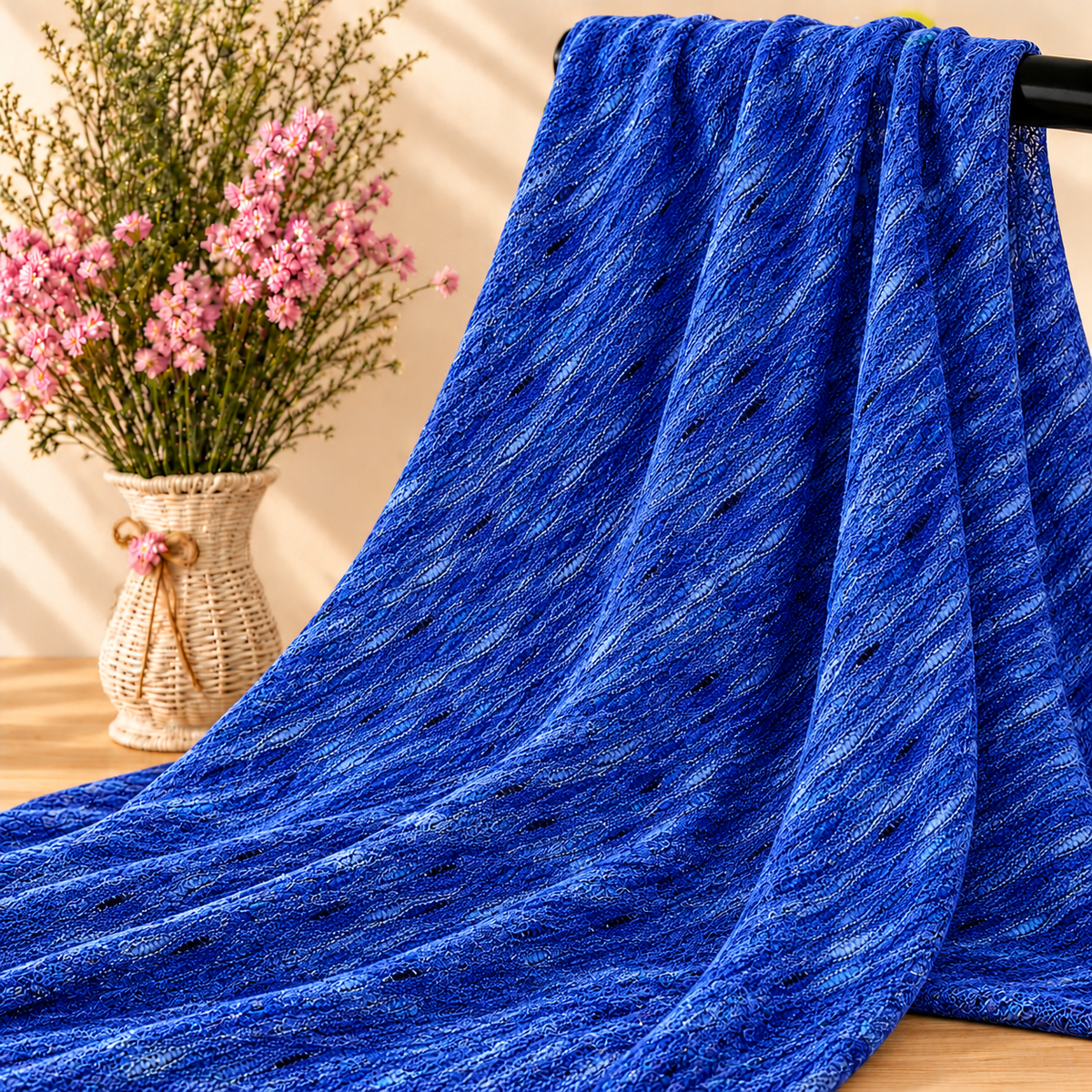 Mise en scène illustrative du tissu bleu texturé sur barre noire avec fleurs