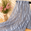 Mise en scène illustrative du tissu transparent gris à motifs ondulés sur barre noire avec fleurs