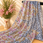 Mise en scène illustrative du tissu transparent léopard et arabesques sur barre noire avec fleurs