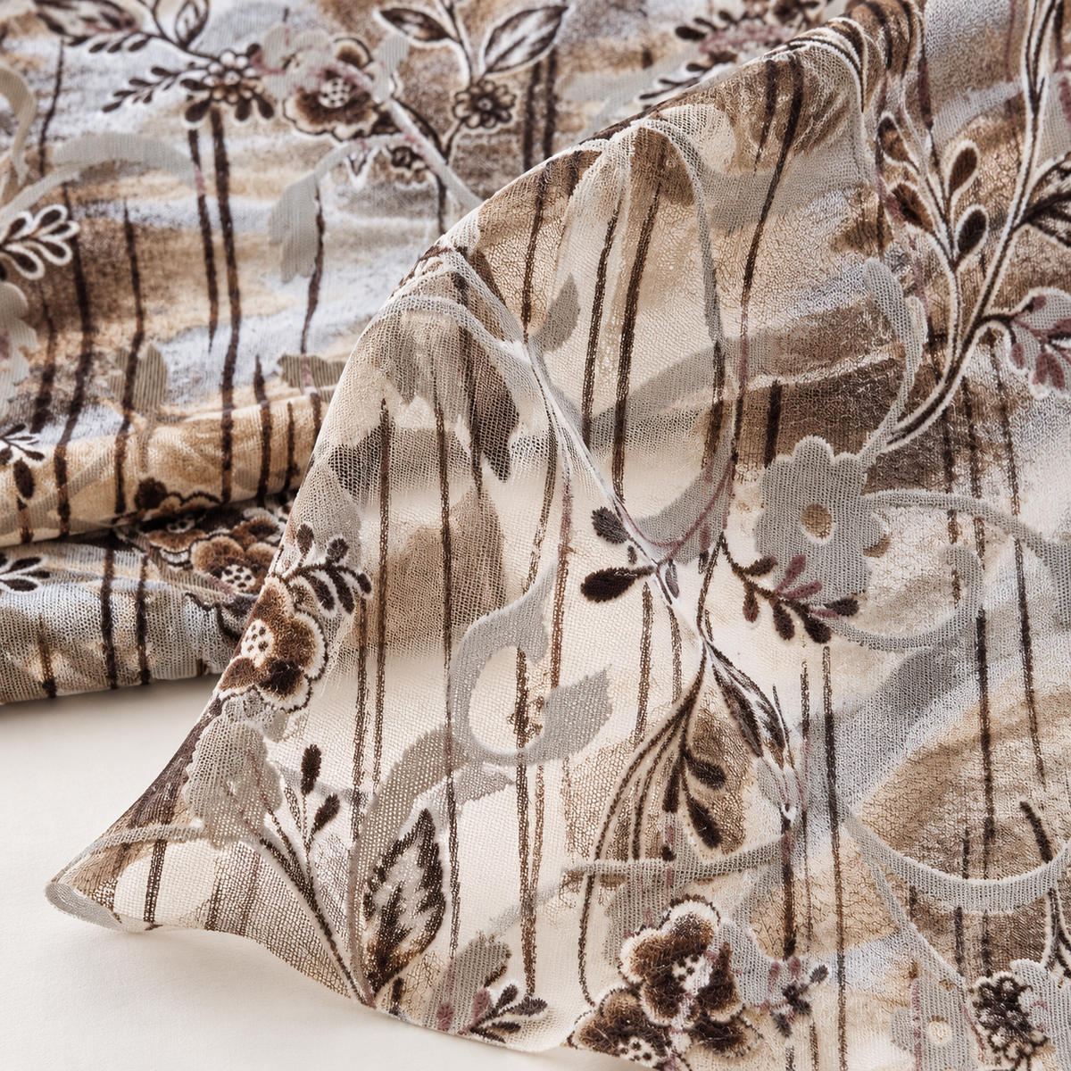 Mise en scène illustrative du velours fleuri beige marron plié montrant sa transparence